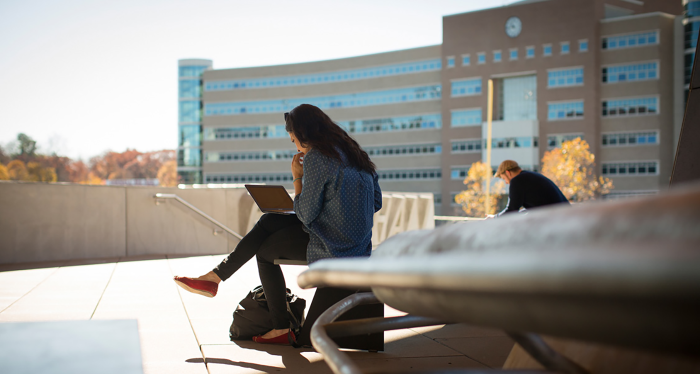 Student uses her laptop in view of Rhodes Hall